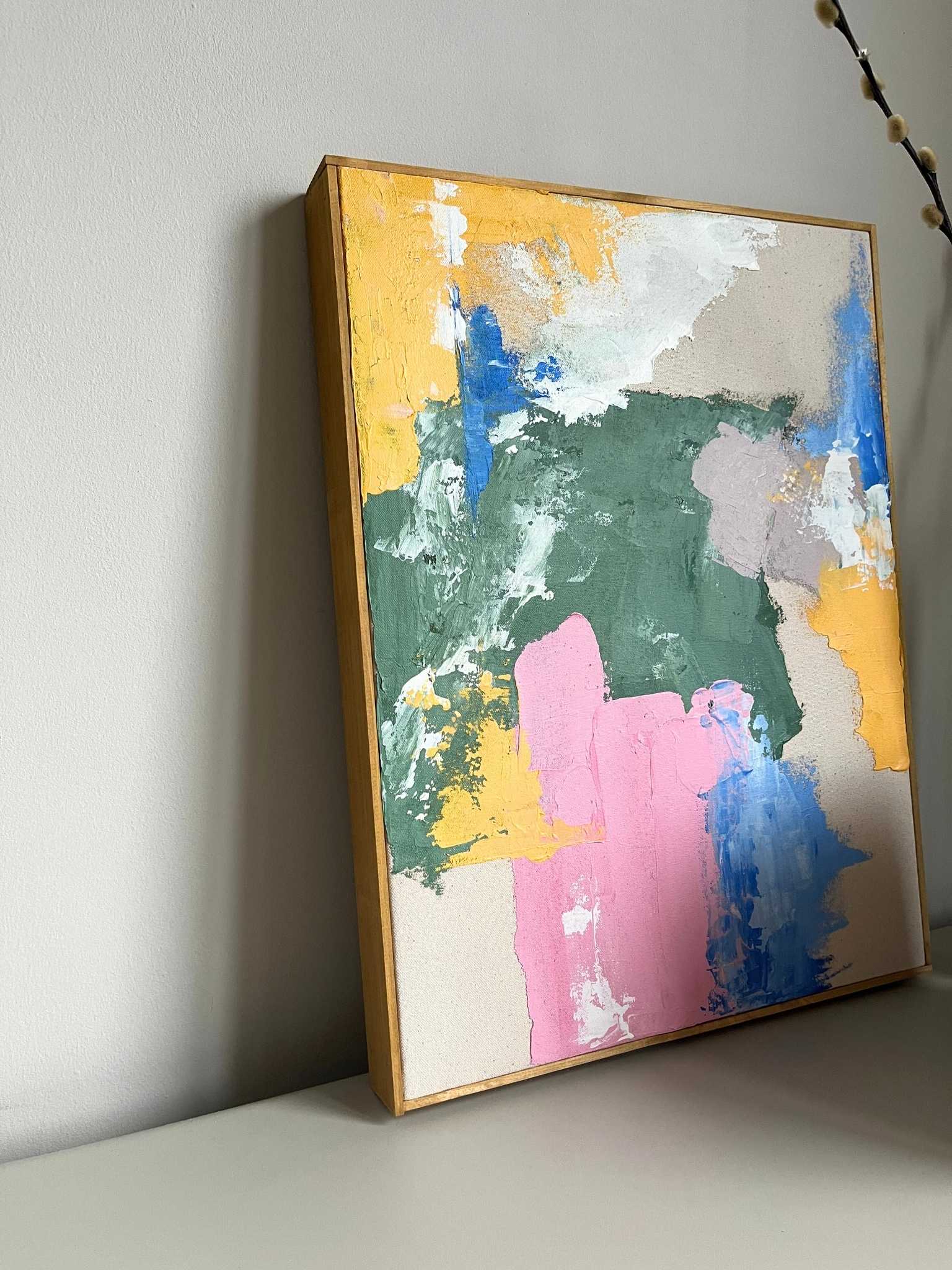 Handcrafted framed abstract canvas artwork created from Plan’s Mix palette, featuring layered green, yellow, pink and blue paint with expressive texture, styled as contemporary wall art on a neutral cabinet.
