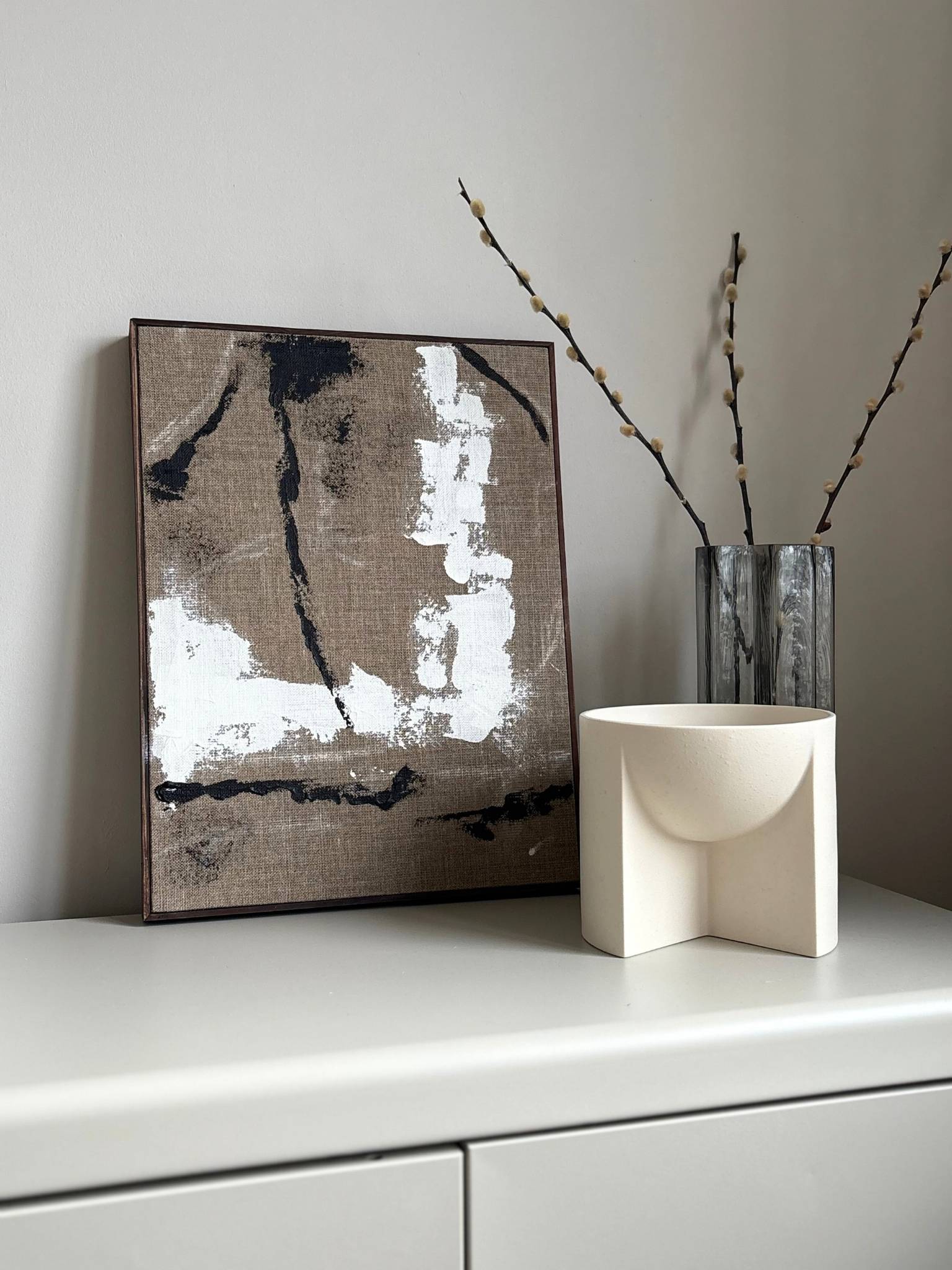 Finished framed monochrome abstract artwork on linen canvas with dark oak edge frame, created using Plan’s monochrome linen palette with expressive black and white marks and visible linen texture, styled in a calm, neutral interior.
