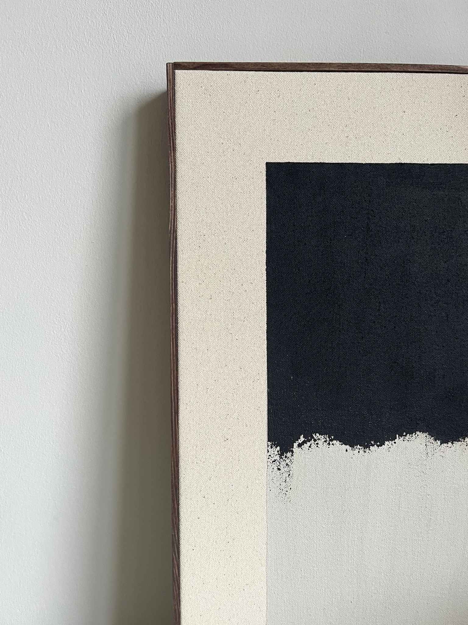 Finished framed monochrome abstract artwork on cotton canvas with dark oak edge frame, created using Plan’s monochrome cotton palette with layered black and white brushstrokes, styled on a shelf in a modern interior.