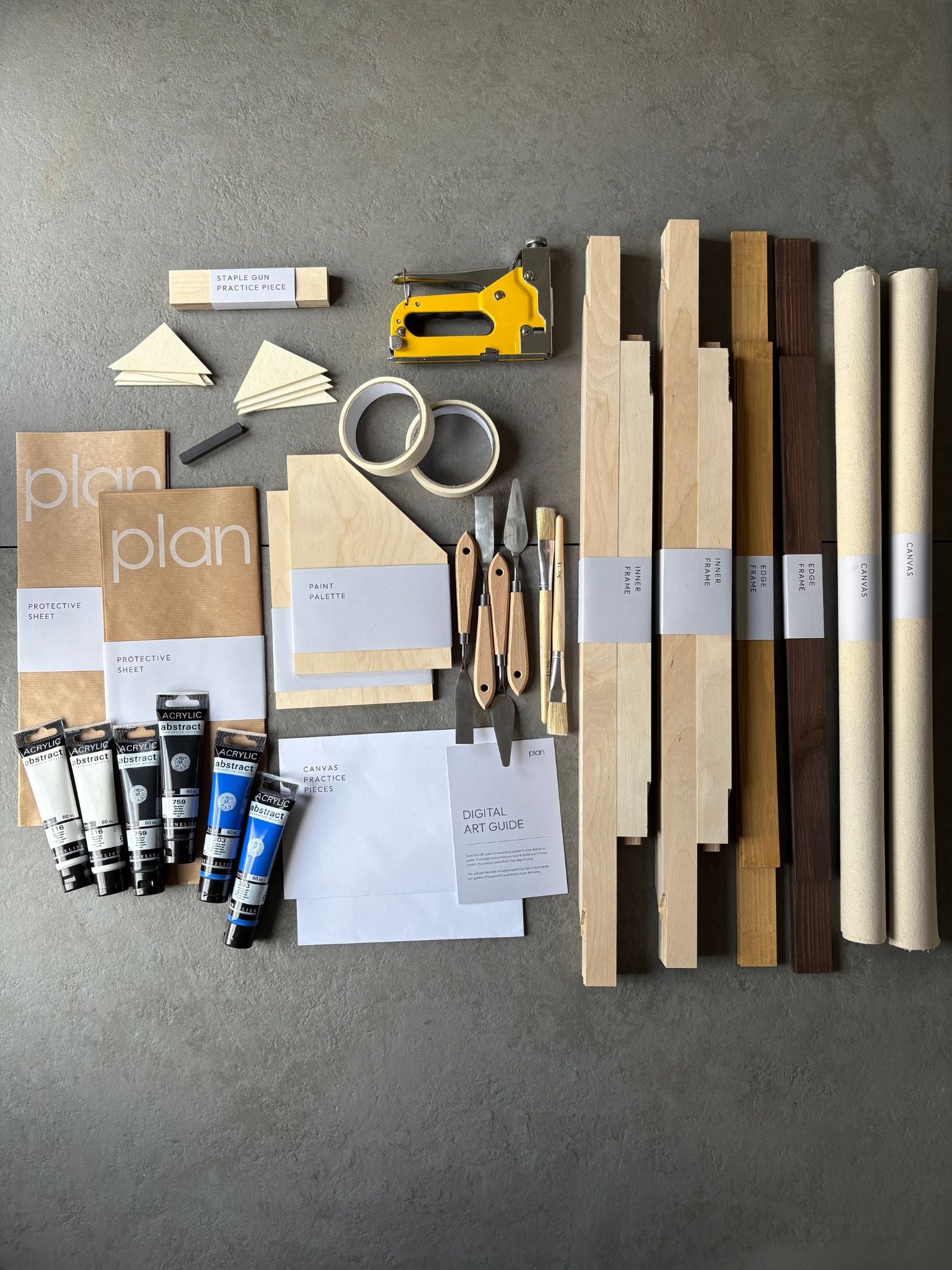 Flatlay of Monochrome 01 Double DIY Art Kit 50x70 cm with oak and dark oak frames, black white and blue paints, masking tape and palette knife — minimal DIY art kit UK for modern interiors.