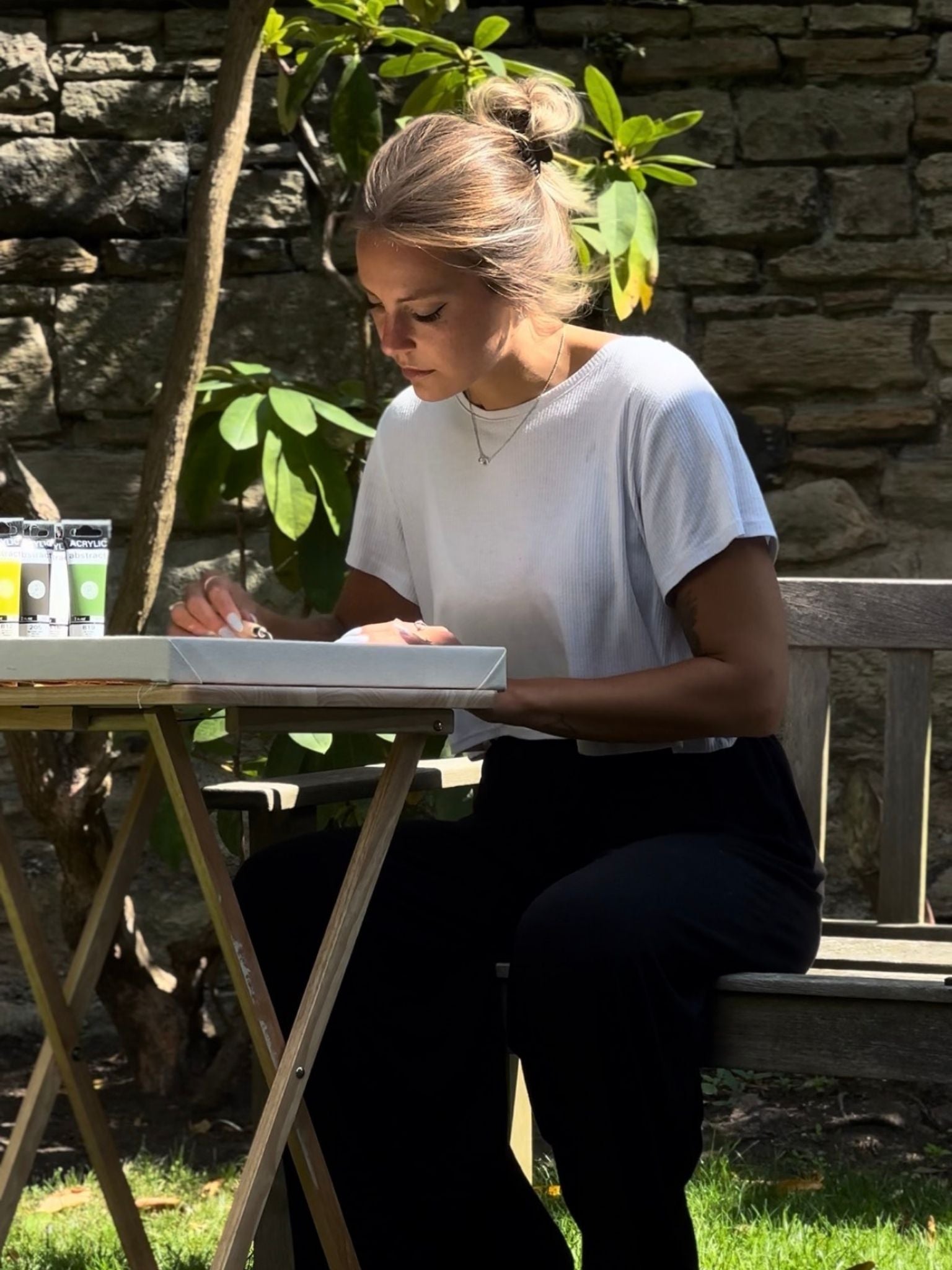 Person painting on a framed canvas outdoors using a Plan DIY art kit, focused and calm creative moment showing painting as a way to slow down and switch off