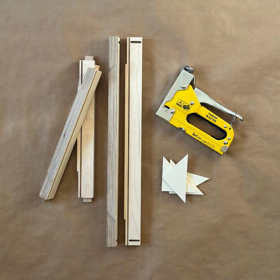 Hands-on DIY framed canvas art kit showing custom inner frame pieces, staple gun and corner supports used to build a framed canvas artwork at home.