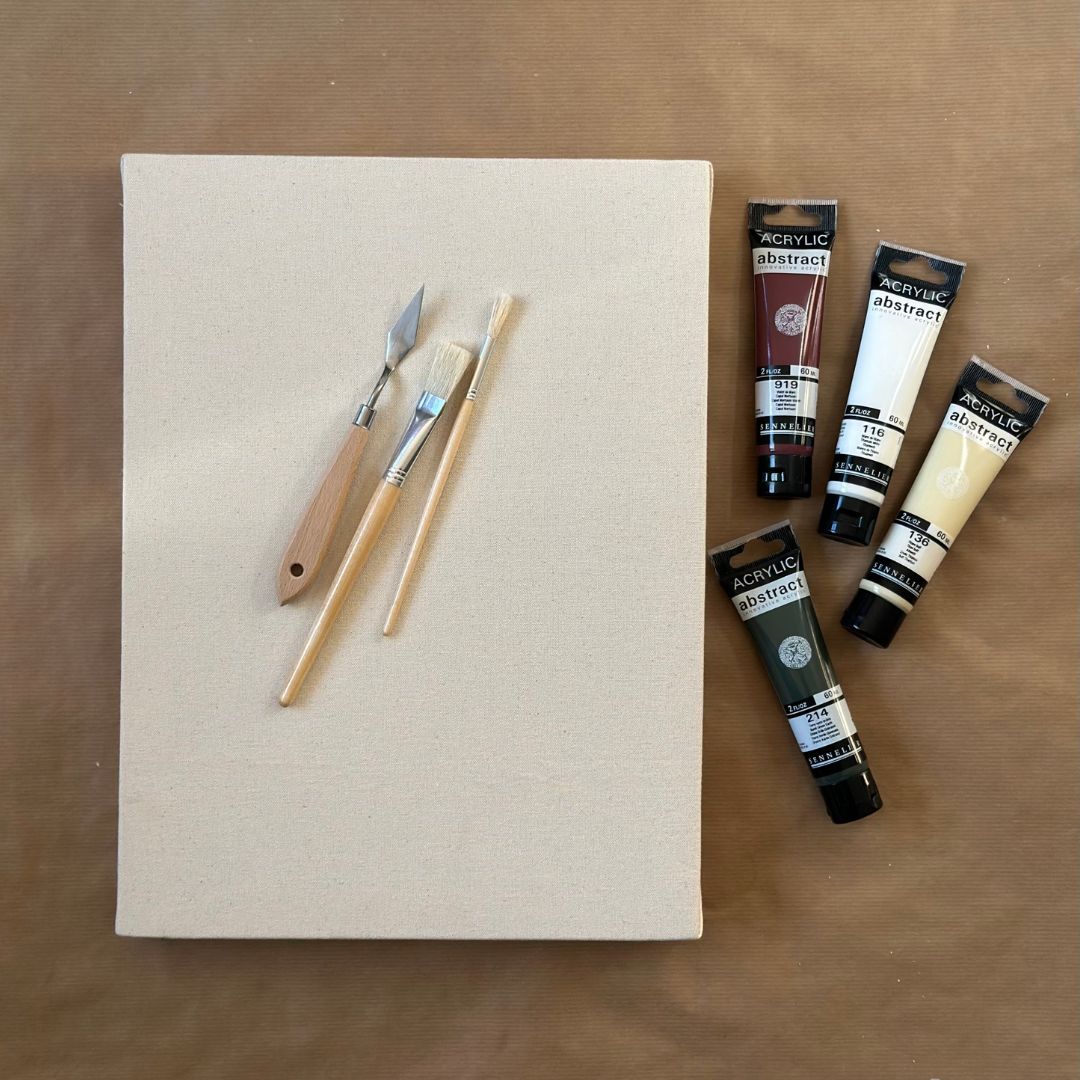 Blank canvas with paint brushes and acrylic paints included in a DIY framed canvas art kit for creating personalised wall art at home.