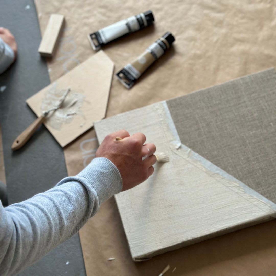 Painting on a stretched raw canvas using brushes and acrylic paints as part of a DIY framed canvas art kit experience.