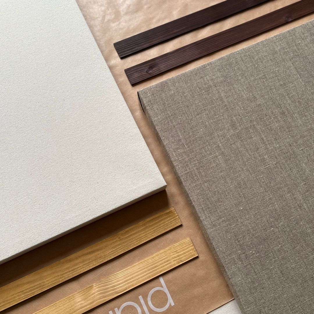Flatlay of handcrafted oak and dark oak edge frames, next to assembled cotton and linen framed canvases made using Plan DIY Art Kits.