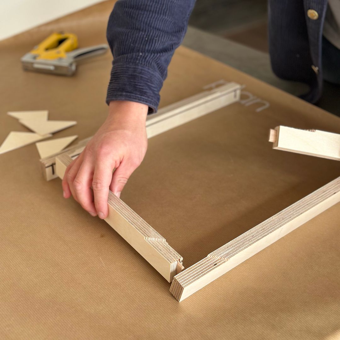 Actively building a custom wooden canvas frame by hand as part of a DIY framed canvas art kit experience.