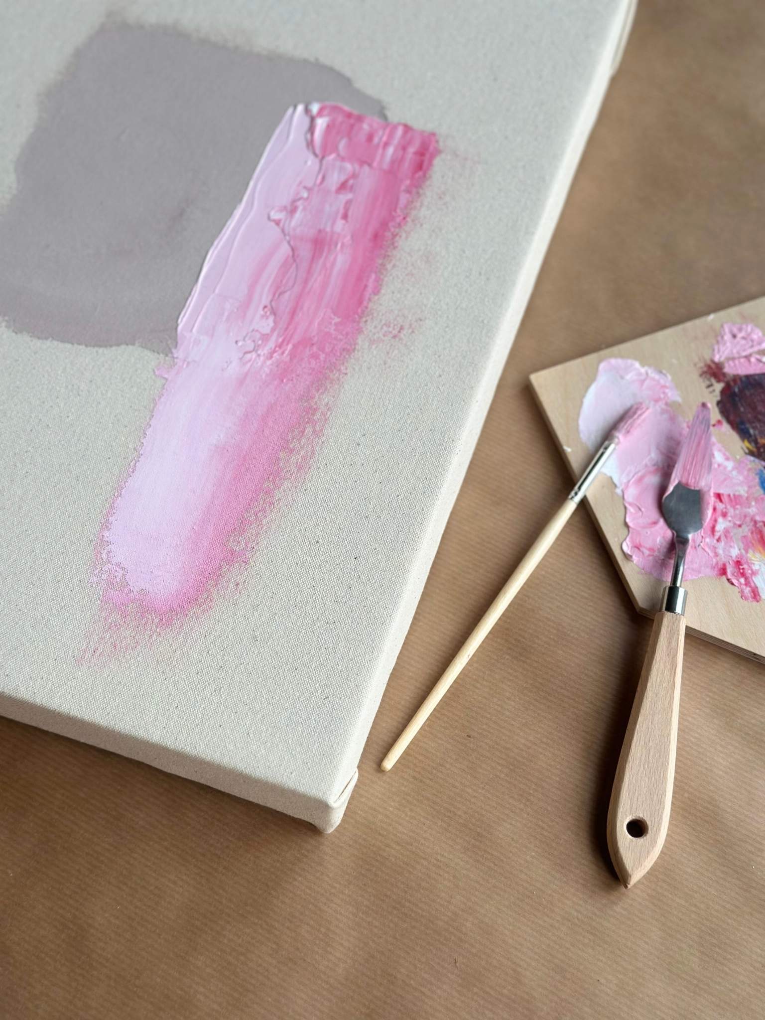 Close-up of paint being applied to a cotton canvas using a Plan DIY framed canvas art kit, showing the first brushstrokes and how to begin painting with confidence