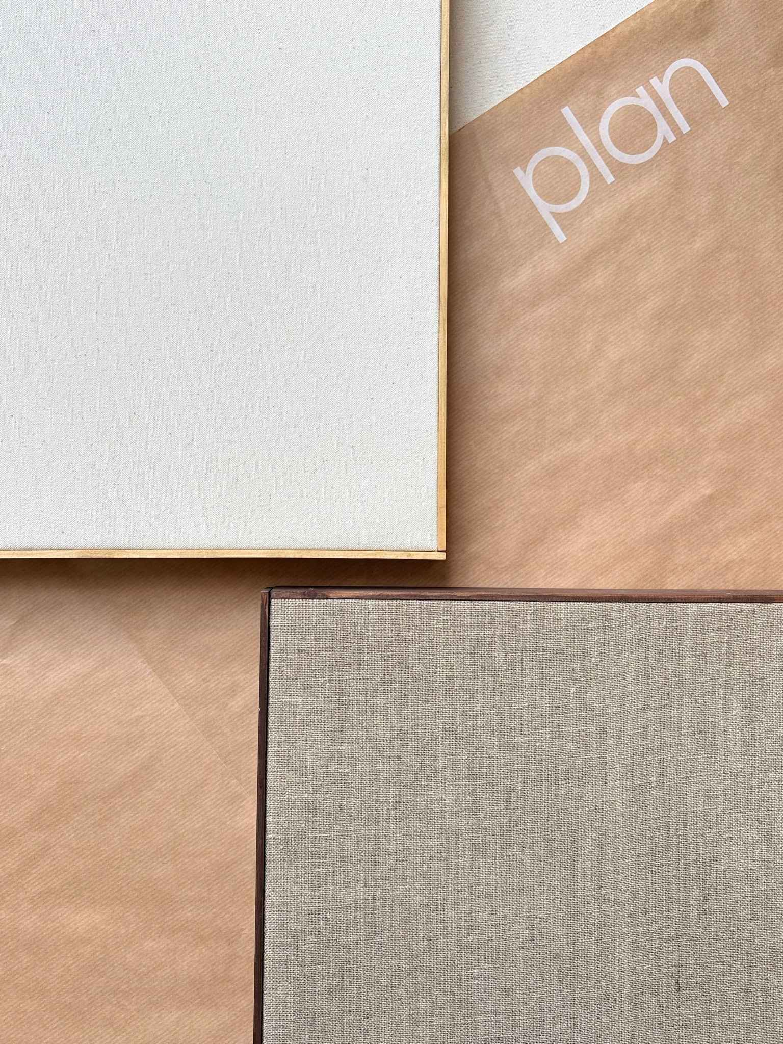 Blank framed canvas art kit laid flat, highlighting the smooth canvas surface, slim wooden edge frame, and Plan-branded protective paper beneath the canvas