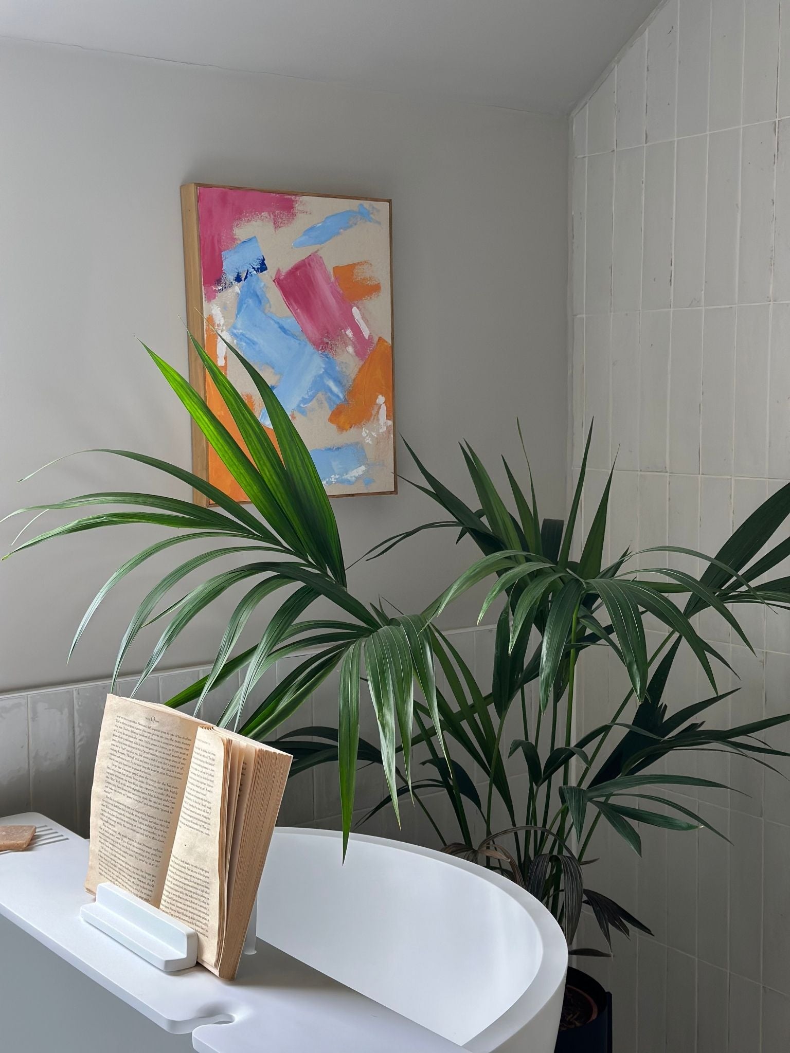Finished abstract canvas art created with the Mix framed canvas art kit, leaning above a freestanding bath with tropical plants, showing bold colour mixing and expressive brushstrokes on canvas.