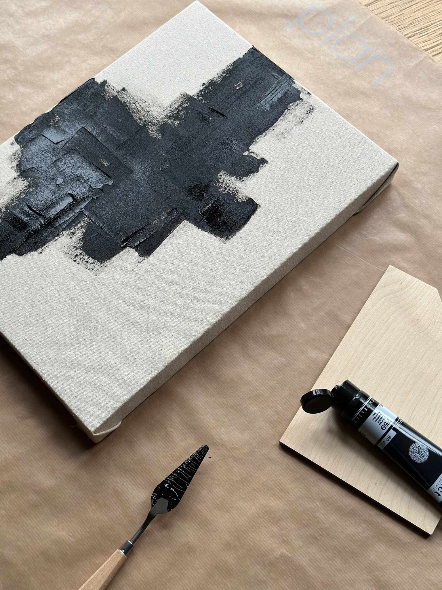 Close-up of abstract monochrome canvas painting in progress, showing black paint layered with textured on cotton canvas.