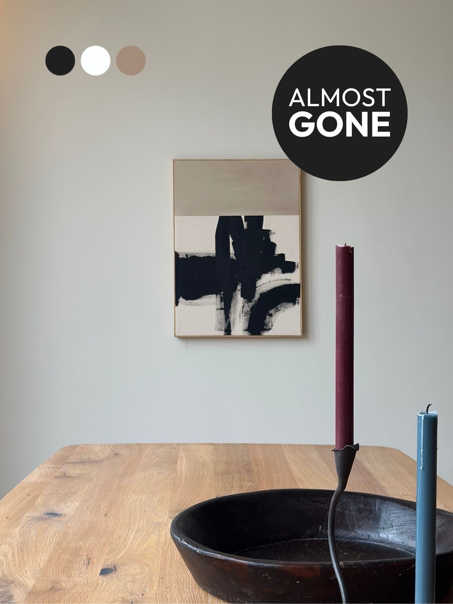 Monochrome abstract framed canvas artwork featuring expressive black brushstrokes on beige cotton canvas, styled in a calm dining space with candles and wooden furniture.