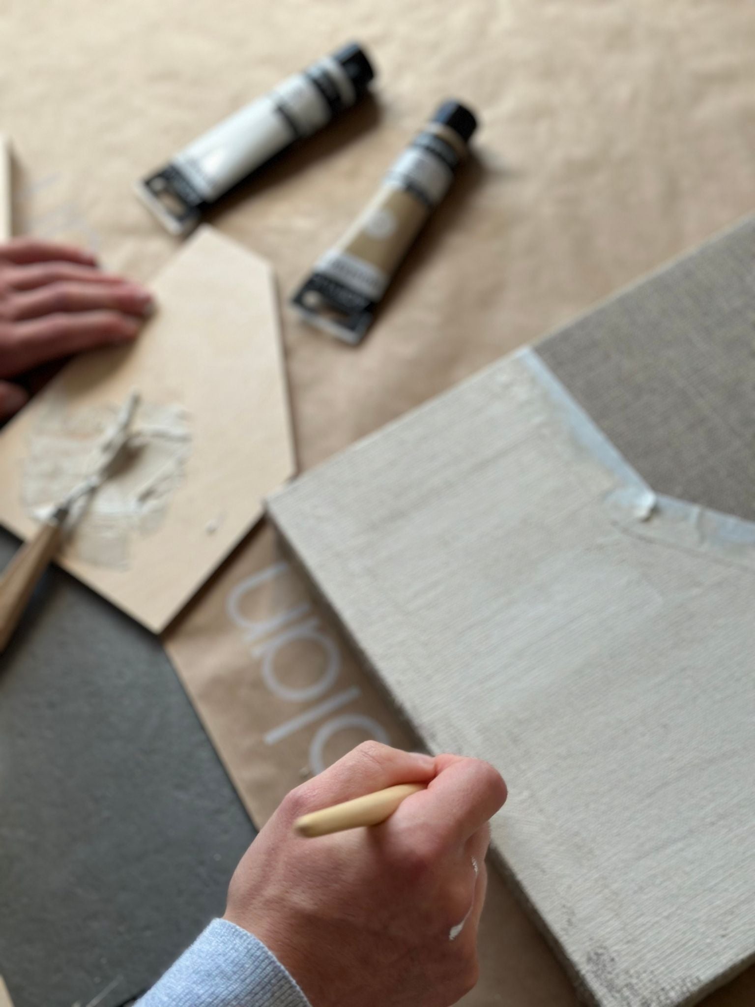 Close-up process of painting on raw linen canvas using beige acrylic paint from a monochrome framed canvas art kit
