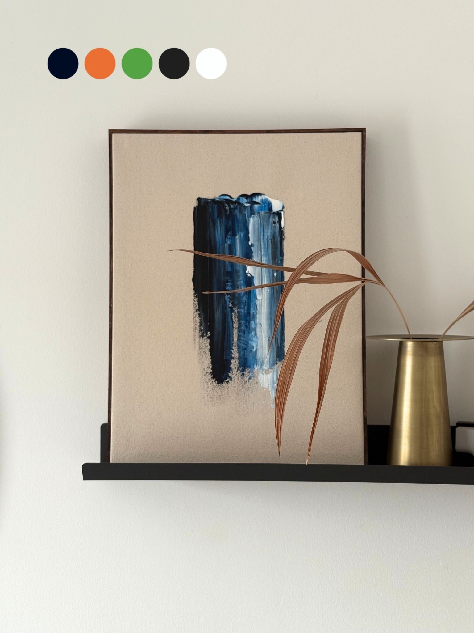 DIY abstract framed canvas art made using navy and bright blue tones, styled on a black wall shelf with brass vase and dried stems, showcasing modern handmade wall art.