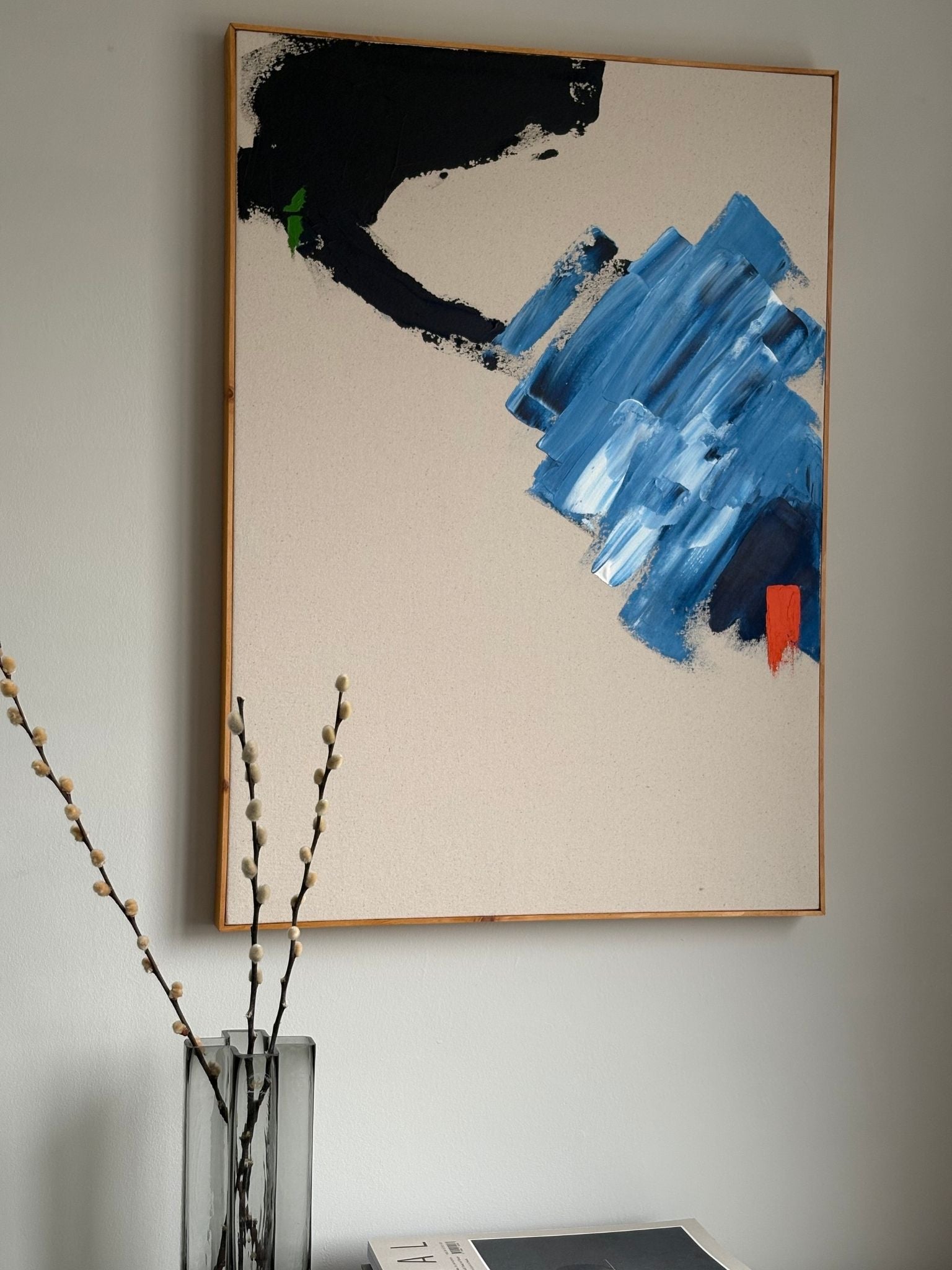 Large abstract framed canvas artwork created with the Navy & Bright art kit, featuring bold navy, blue and black brushstrokes with a bright orange accent, styled above a shelf.