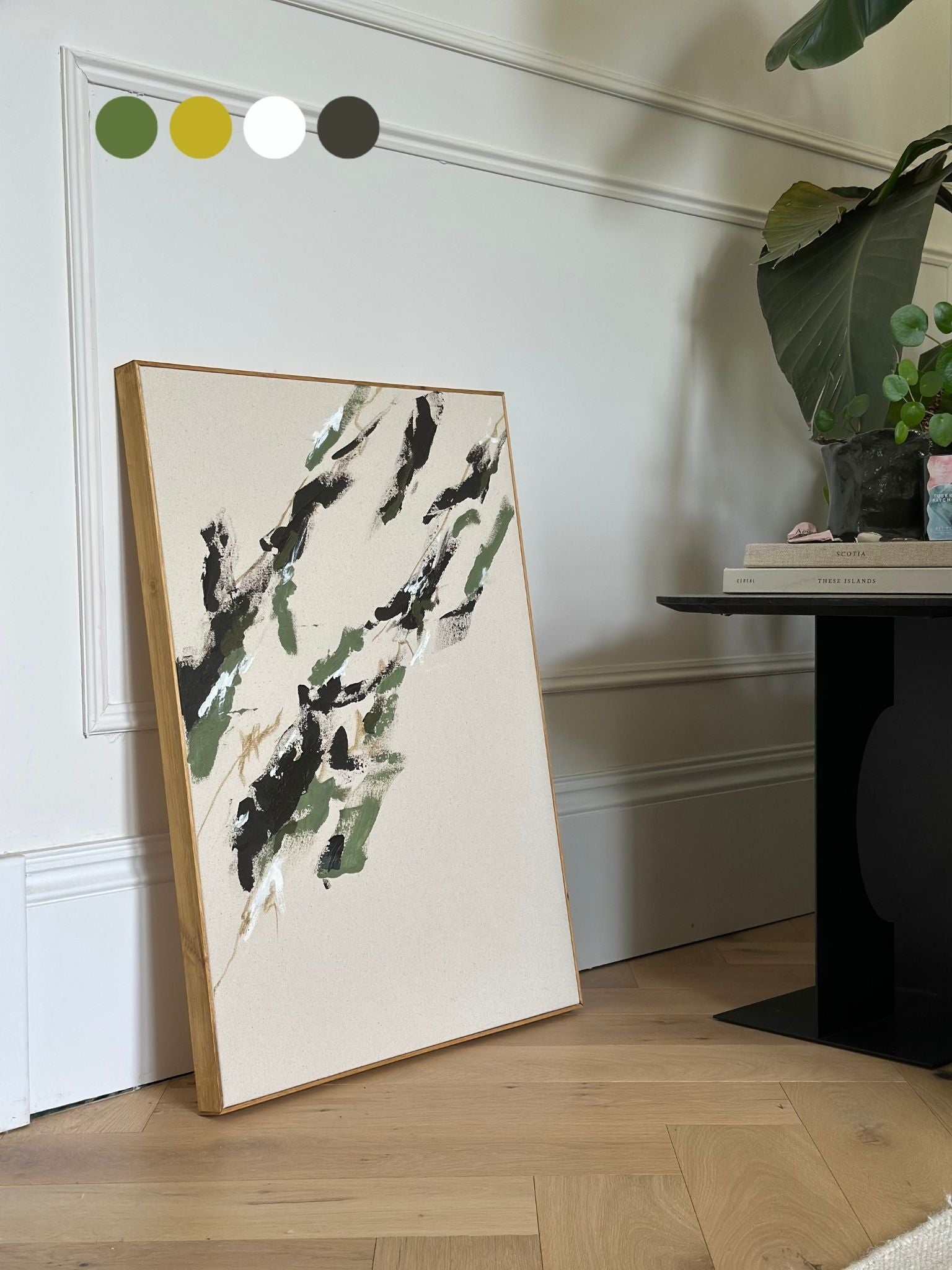 Finished abstract artwork created with the Plan DIY framed canvas art kit in olive tones, shown on cotton canvas with a handcrafted oak edge frame, leaning against wall in styled home