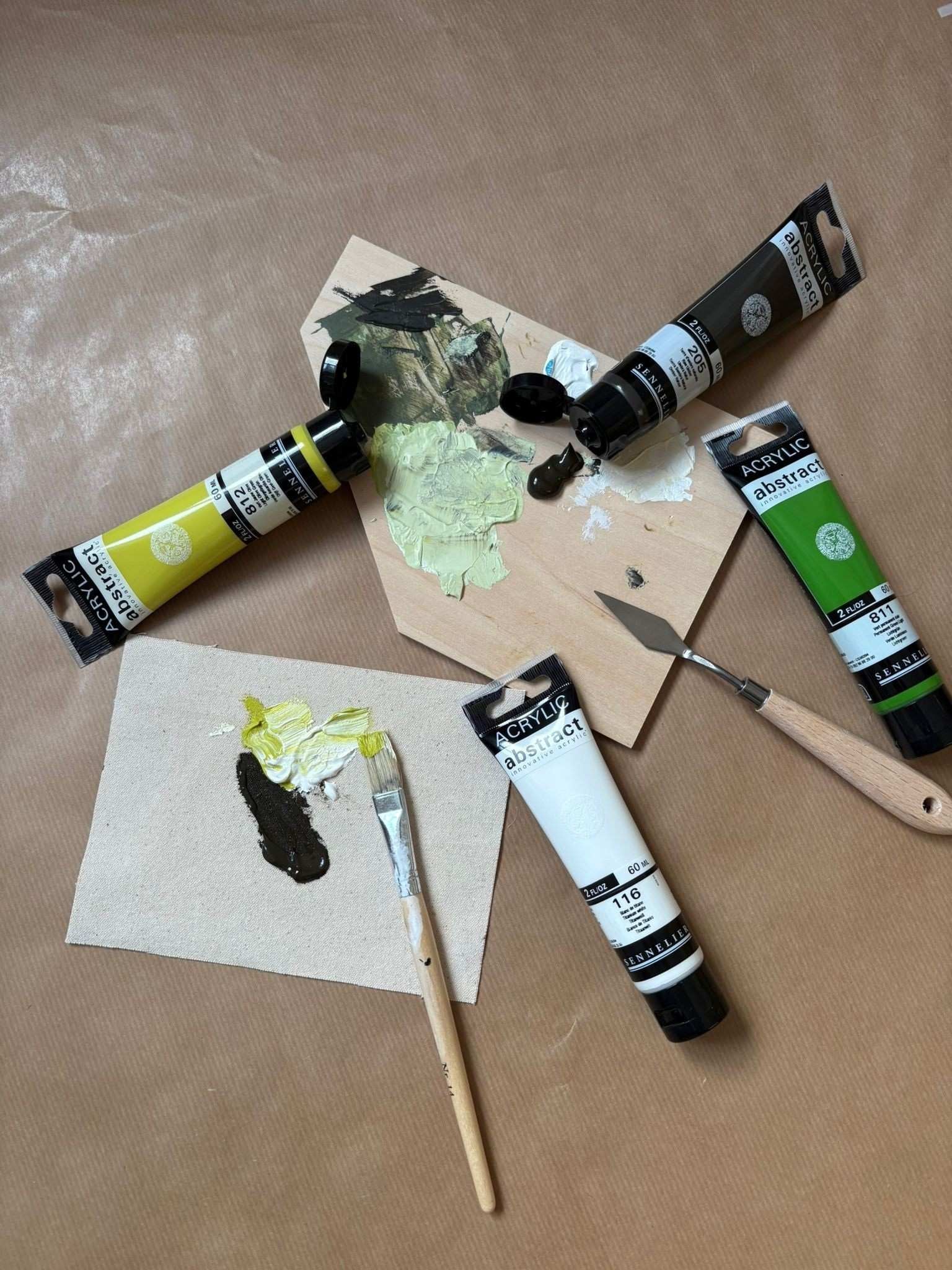 Olive colour palette paints and tools included in the Plan DIY framed canvas art kit, showing acrylic paints, palette knife, brush and colour mixing on canvas