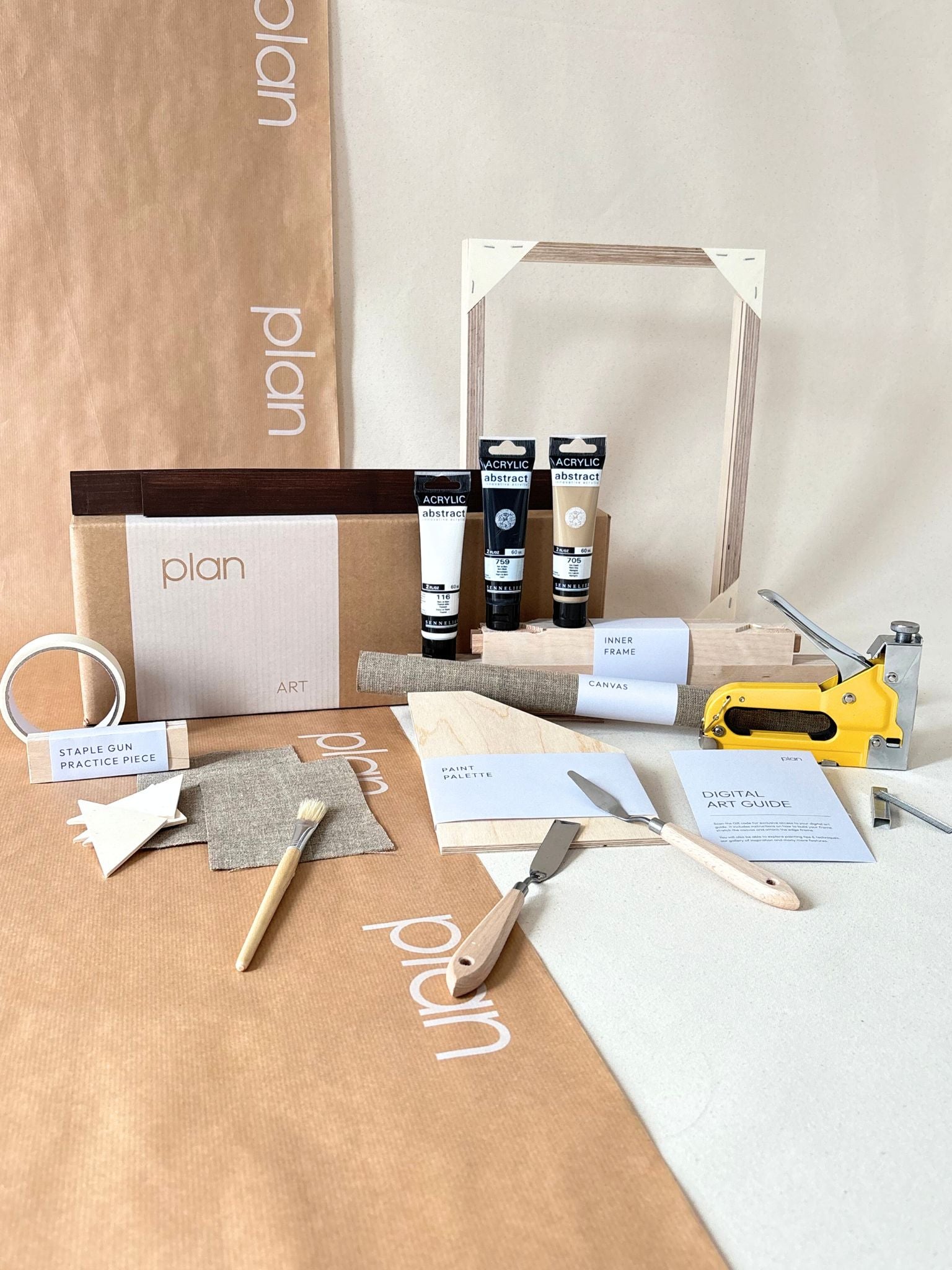 Monochrome framed linen canvas artwork leaning on a bench, featuring white geometric shapes on raw linen canvas, styled with ceramic vase and soft furnishings.