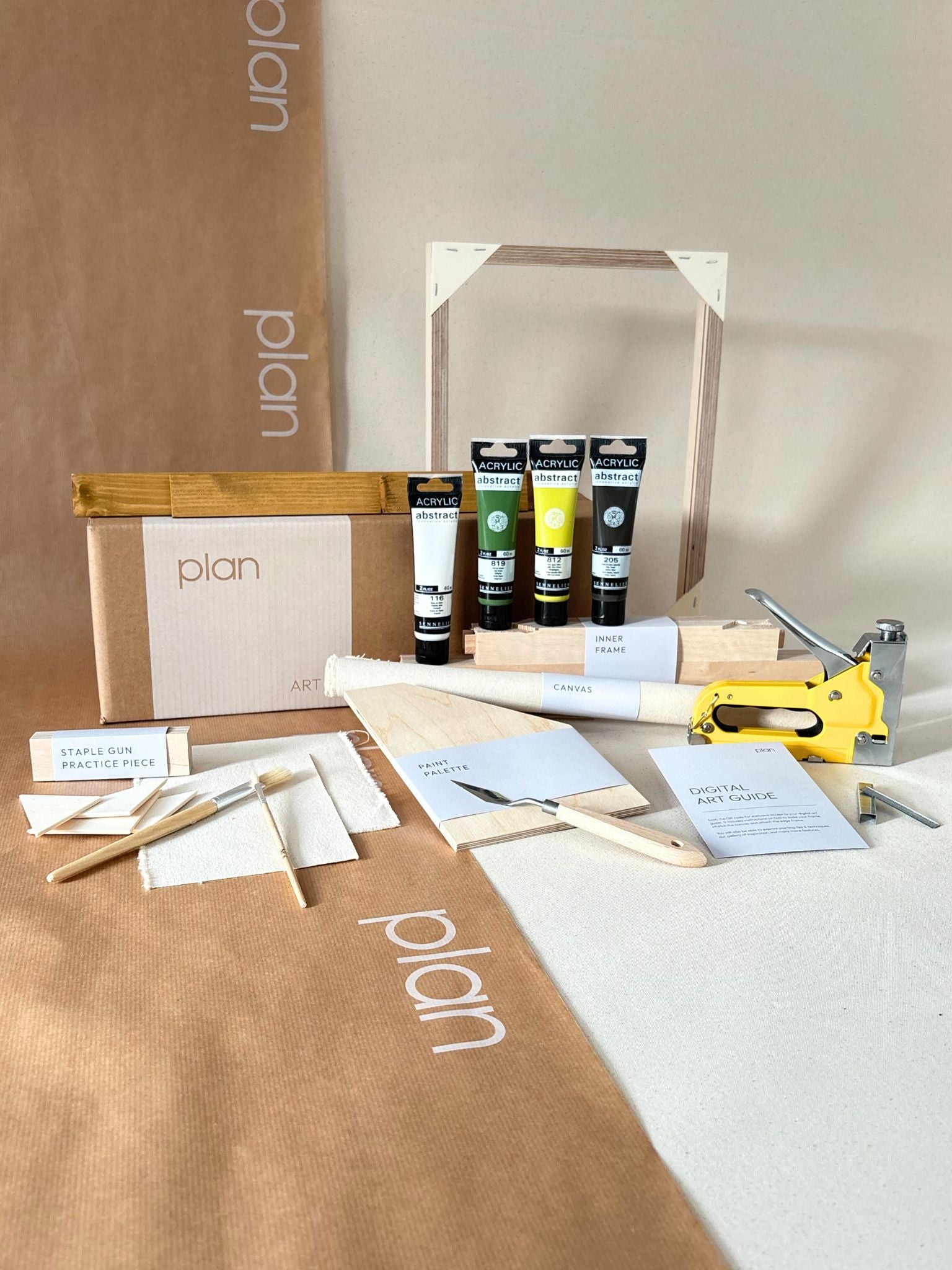 Finished abstract artwork created with the Plan DIY framed canvas art kit in olive tones, shown on cotton canvas with a handcrafted oak edge frame, leaning against wall in styled home