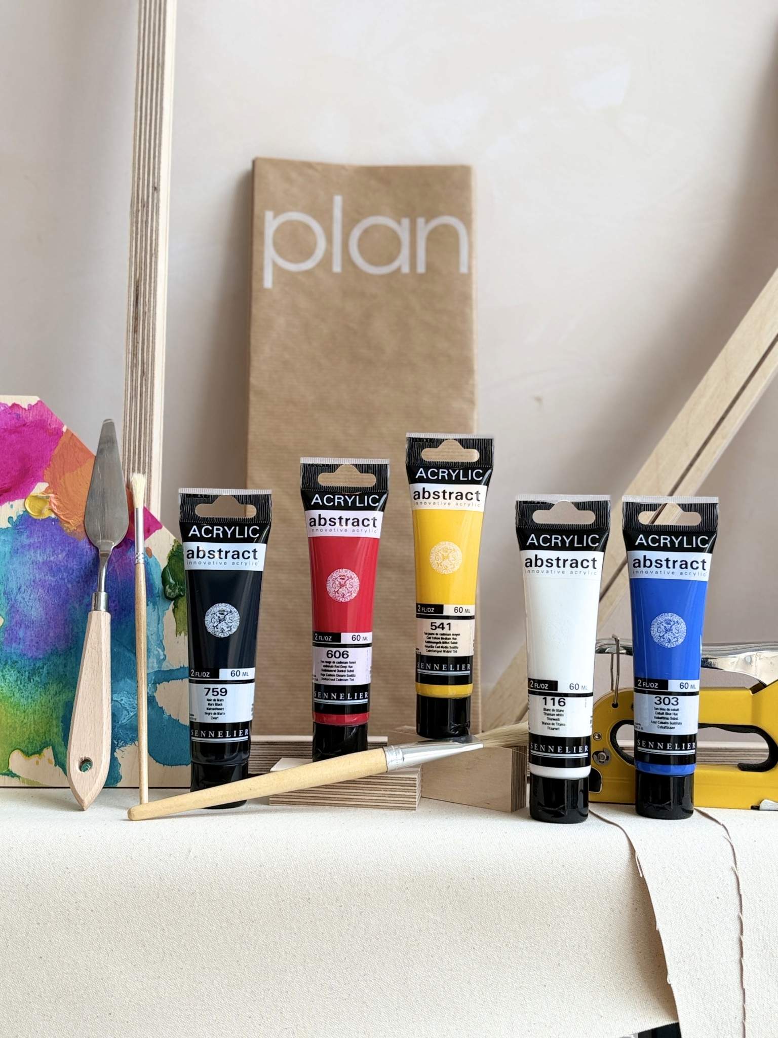 DIY framed canvas art kit with bold primary colour palette, acrylic paints, artist tools, cotton canvas fabric, wooden frame pieces and Plan protective sheet.