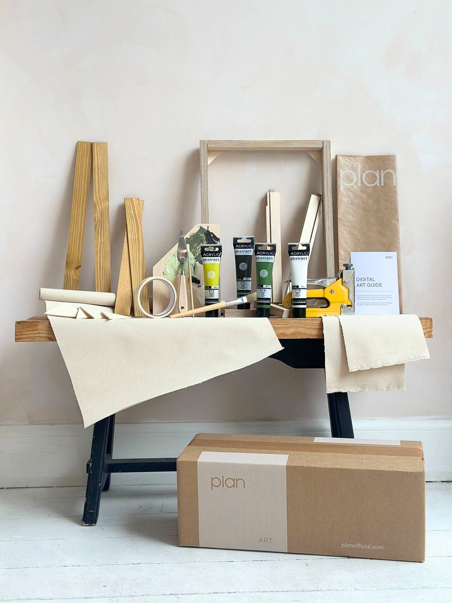 Finished abstract artwork created with the Plan DIY framed canvas art kit in olive tones, shown on cotton canvas with a handcrafted oak edge frame, leaning against wall in styled home