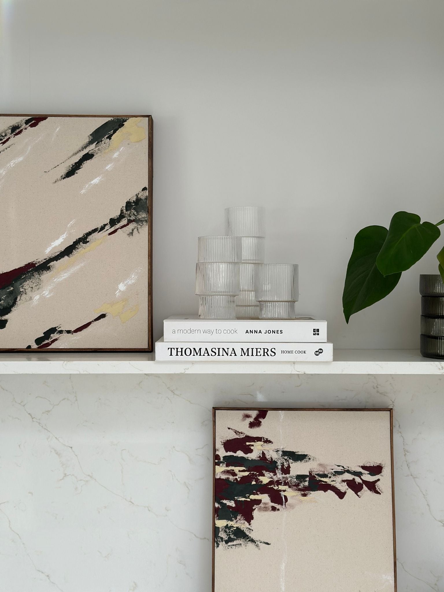 Close-up styled view of two forest red framed artworks on a kitchen shelf, highlighting texture, brushwork and cotton canvas finish.