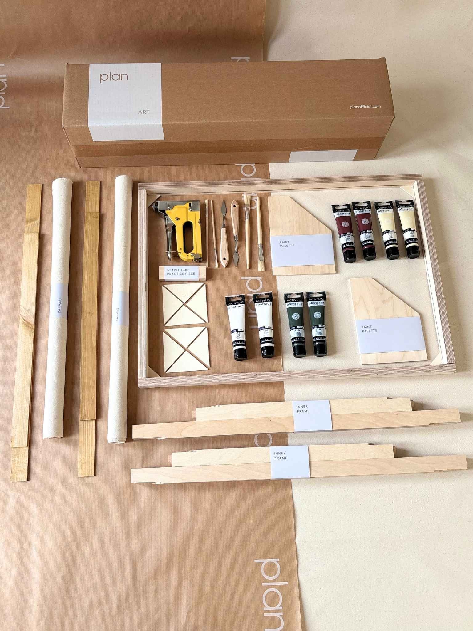 Everything you need to create your own framed artwork at home, shown as a Forest Red double framed canvas art kit with two canvases, handcrafted oak frames, acrylic paints, brushes, palette knives and staple gun laid out flat