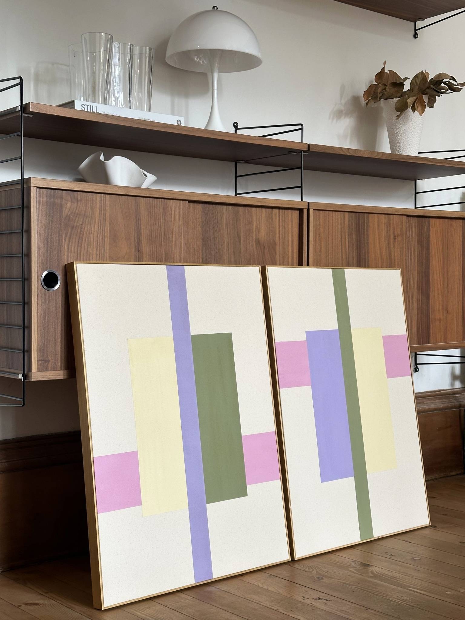 Two large DIY framed canvas artworks with geometric colour blocks and oak frame, styled against mid-century wooden shelving, modern abstract wall art for home