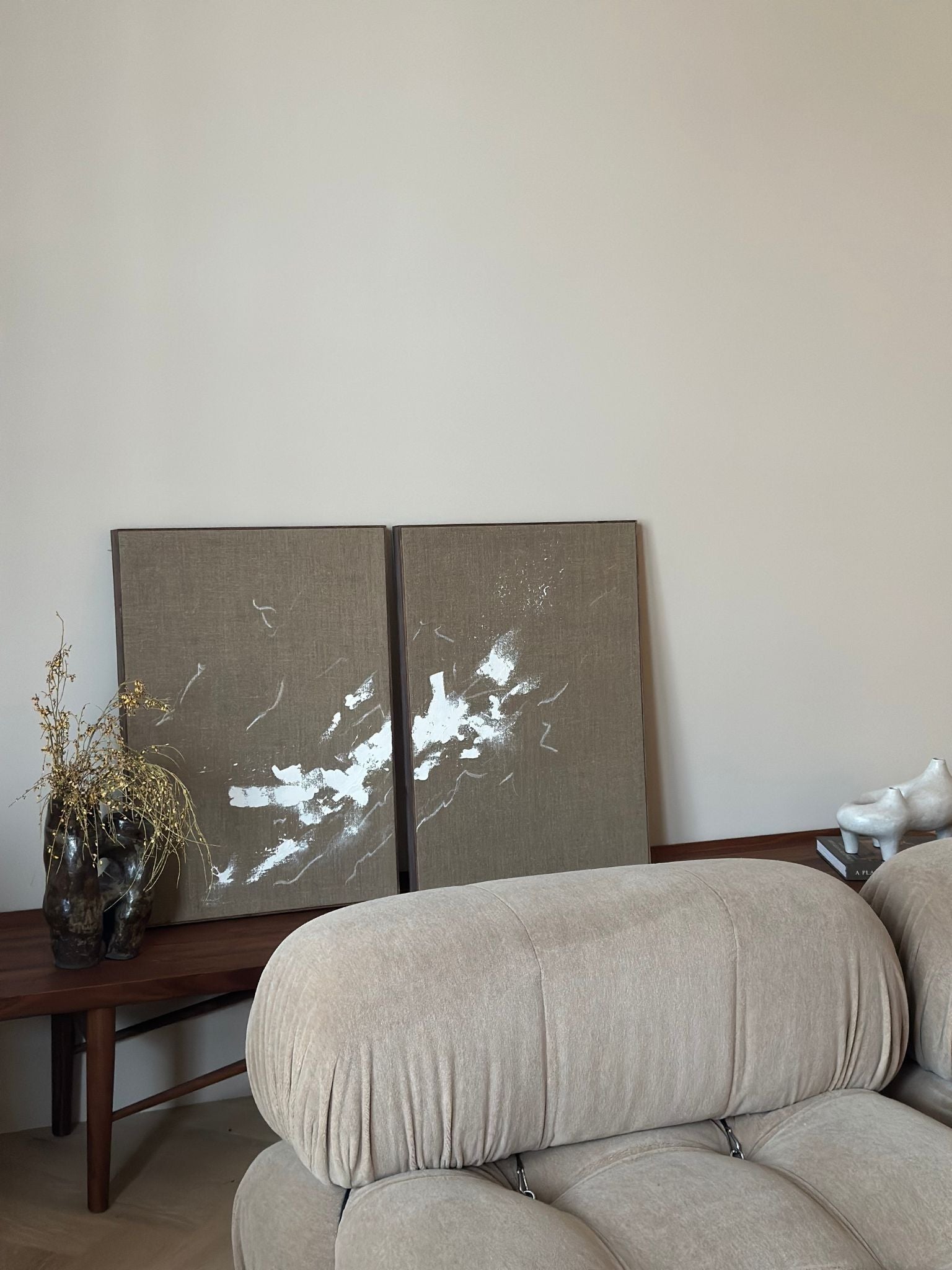 Monochrome linen framed canvas double artwork displayed behind a sofa in a calm, neutral interior setting