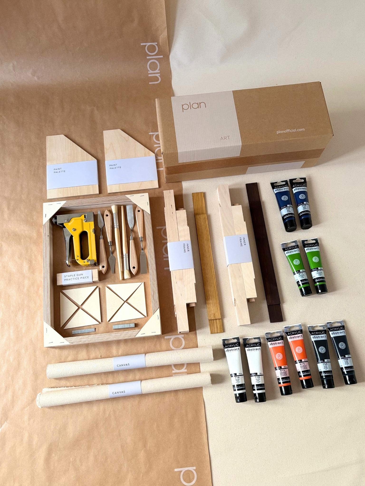 Two finished abstract artworks created with the Navy & Bright double framed canvas art kit, shown side by side on the floor, featuring bold blue, black and accent colour brushstrokes on raw cotton canvas with handcrafted oak and dark oak edge frames.