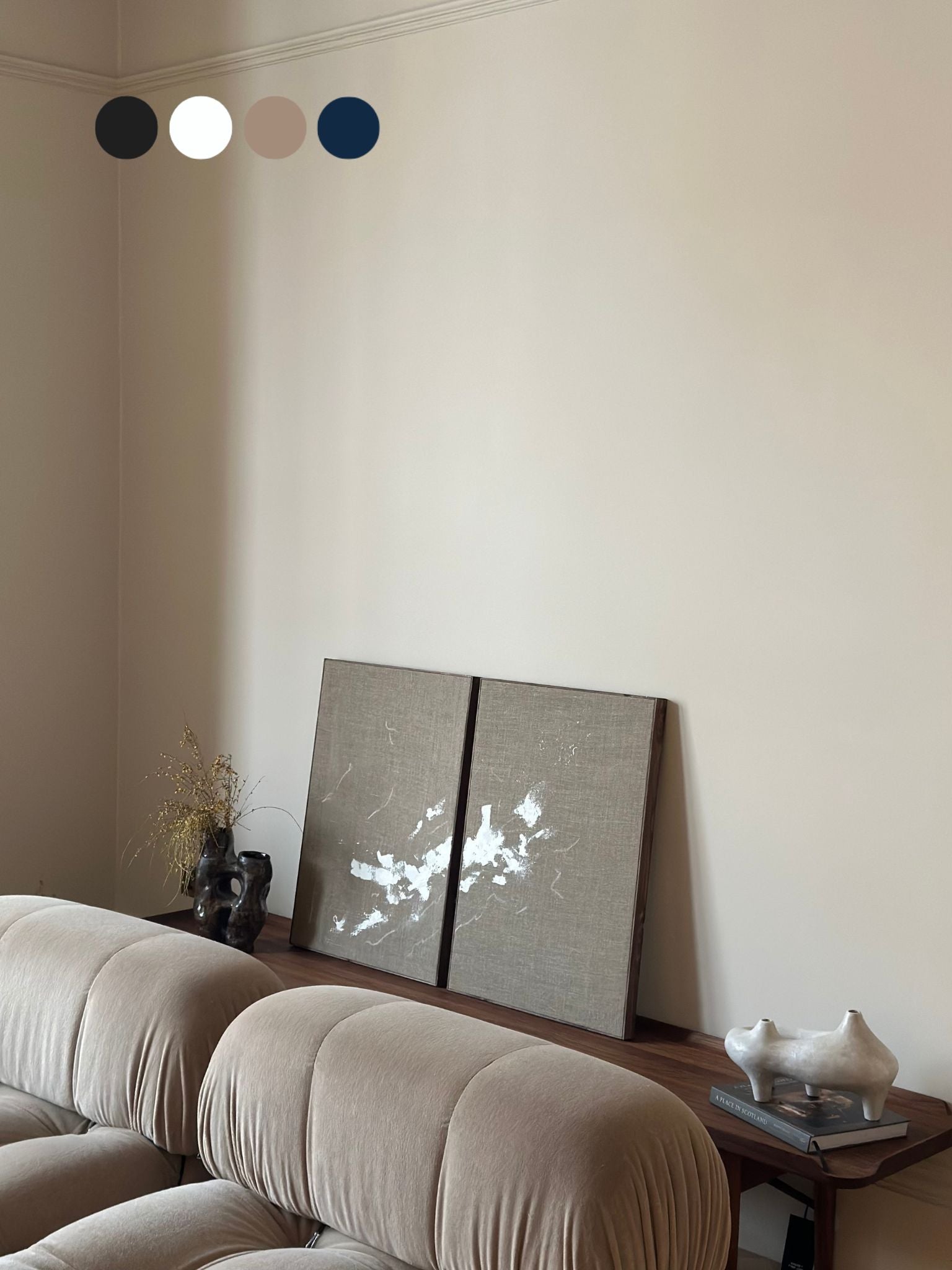 Two finished monochrome linen framed canvases with expressive white brushstrokes, styled on a wooden console in a neutral living room.
