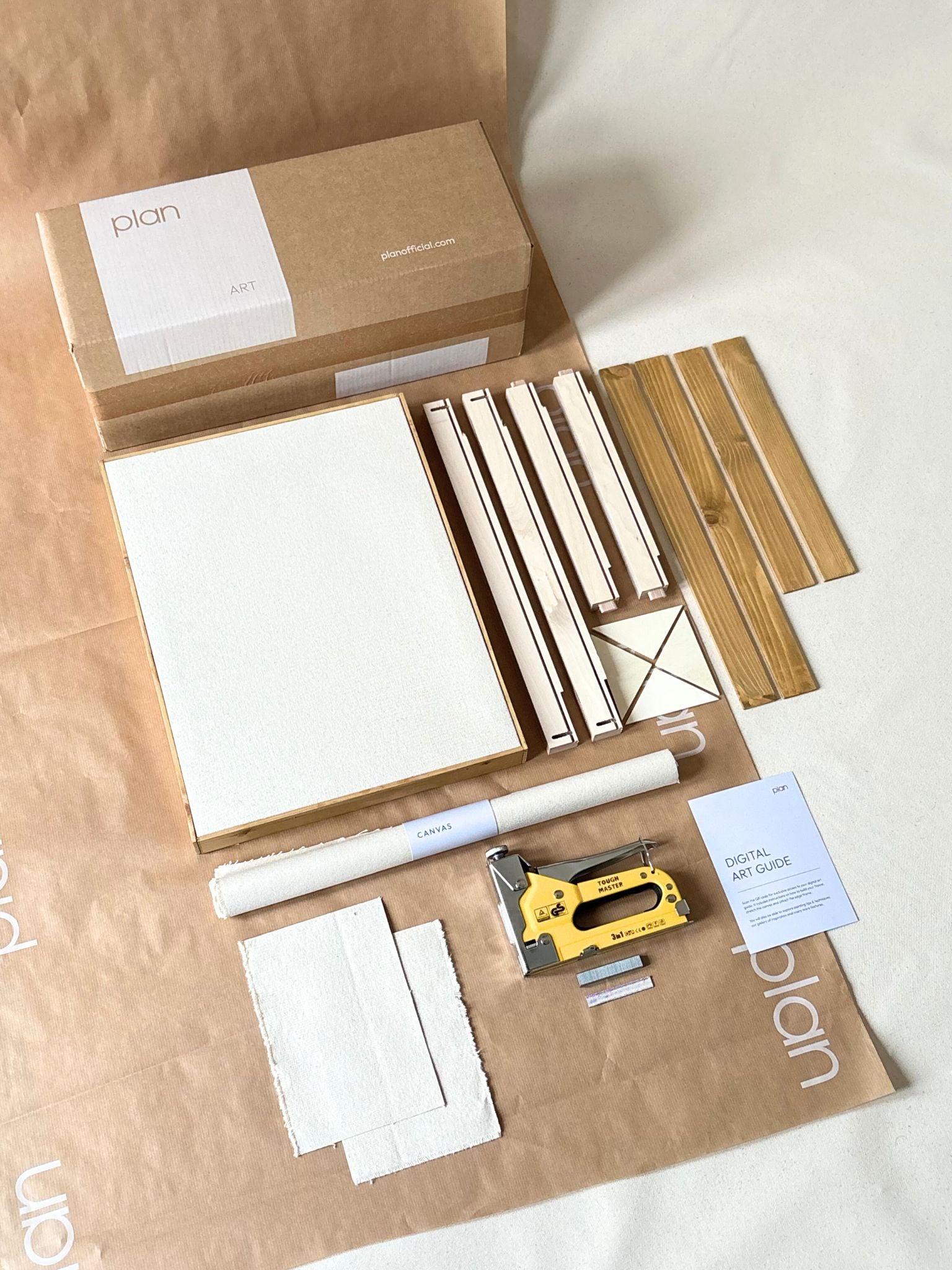 Single blank framed cotton canvas from a DIY art kit styled above a sofa with floor lamp in a calm, neutral living room.