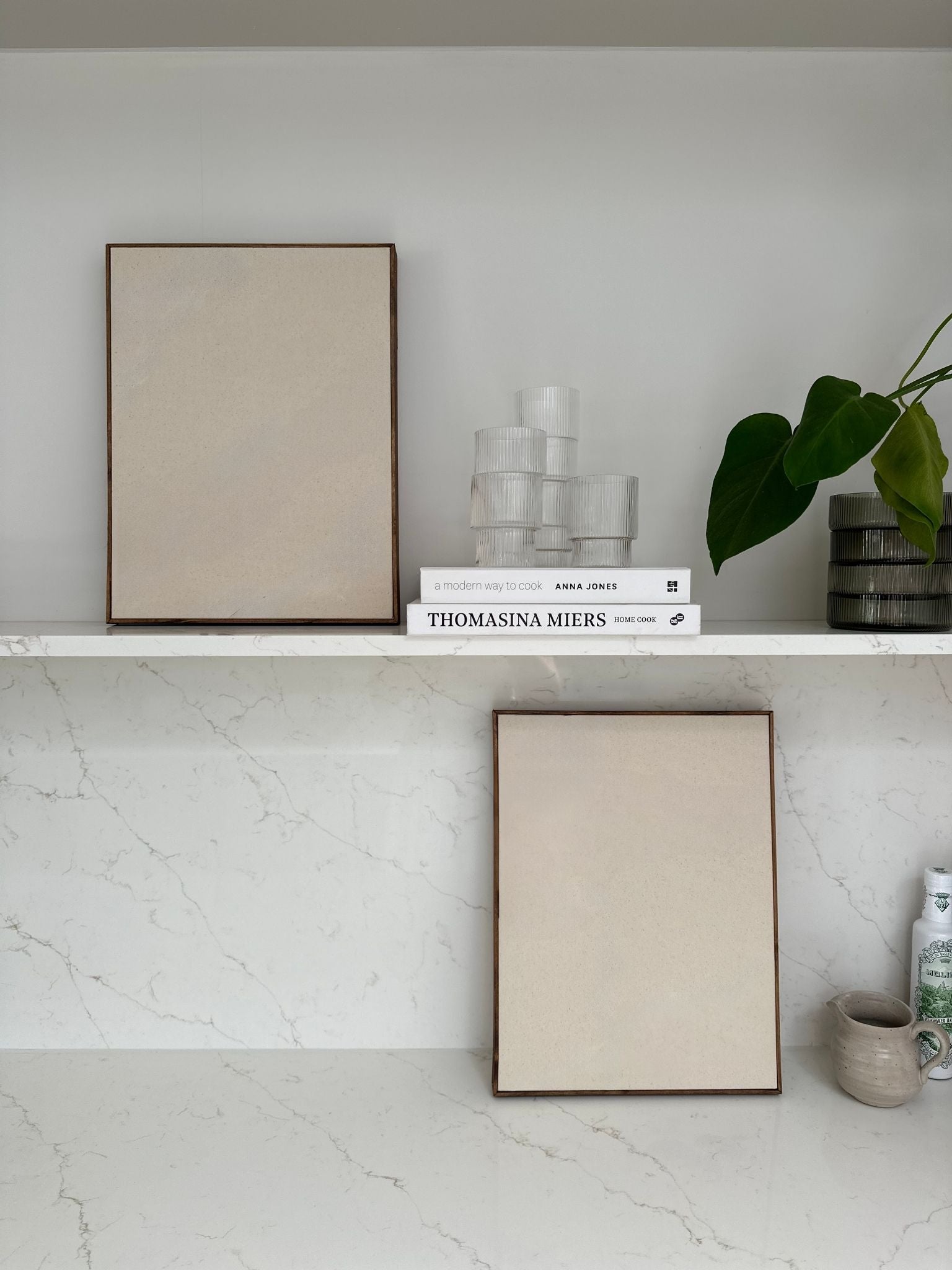 Blank framed cotton canvases from a DIY art kit styled on kitchen shelves with books, glassware and neutral home décor.