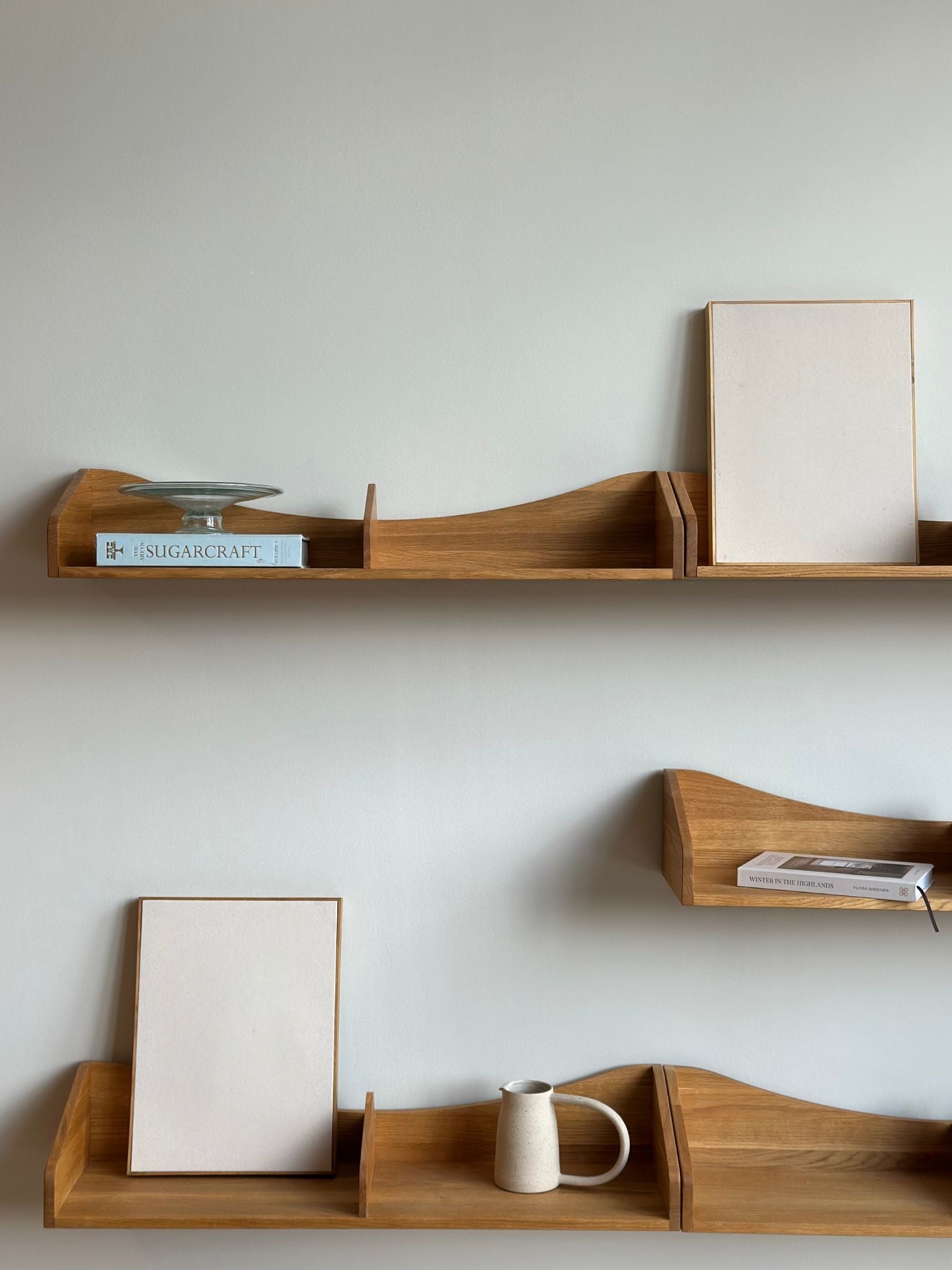 Two blank framed cotton canvases from a DIY framed art kit styled on wooden wall shelves in a minimalist home interior.
