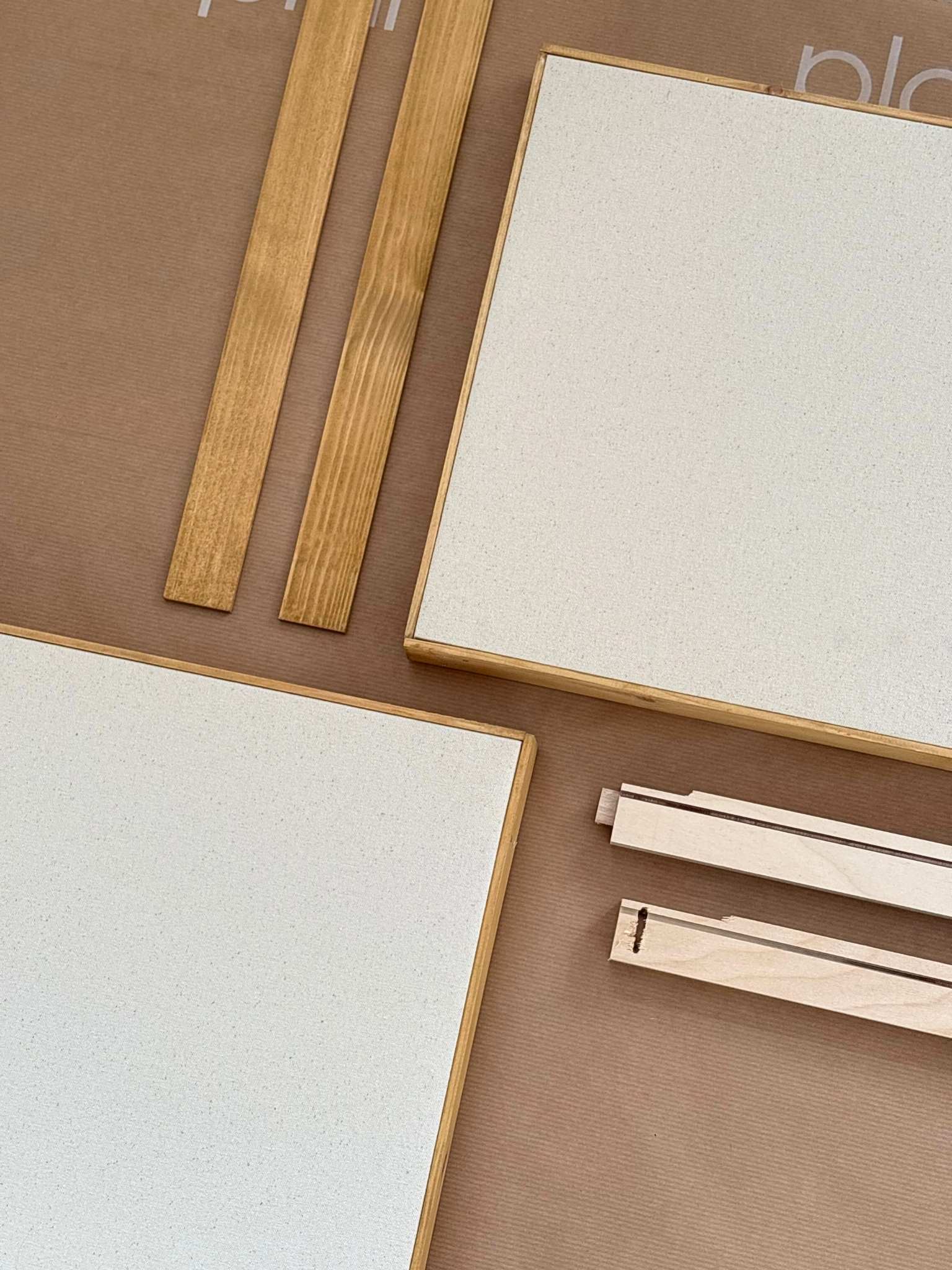 DIY framed cotton canvas art kit flat lay with pre-stretched canvases, wooden edge frame pieces and inner frame bars, highlighting the build-your-own frame system included in Plan’s premium canvas art kits