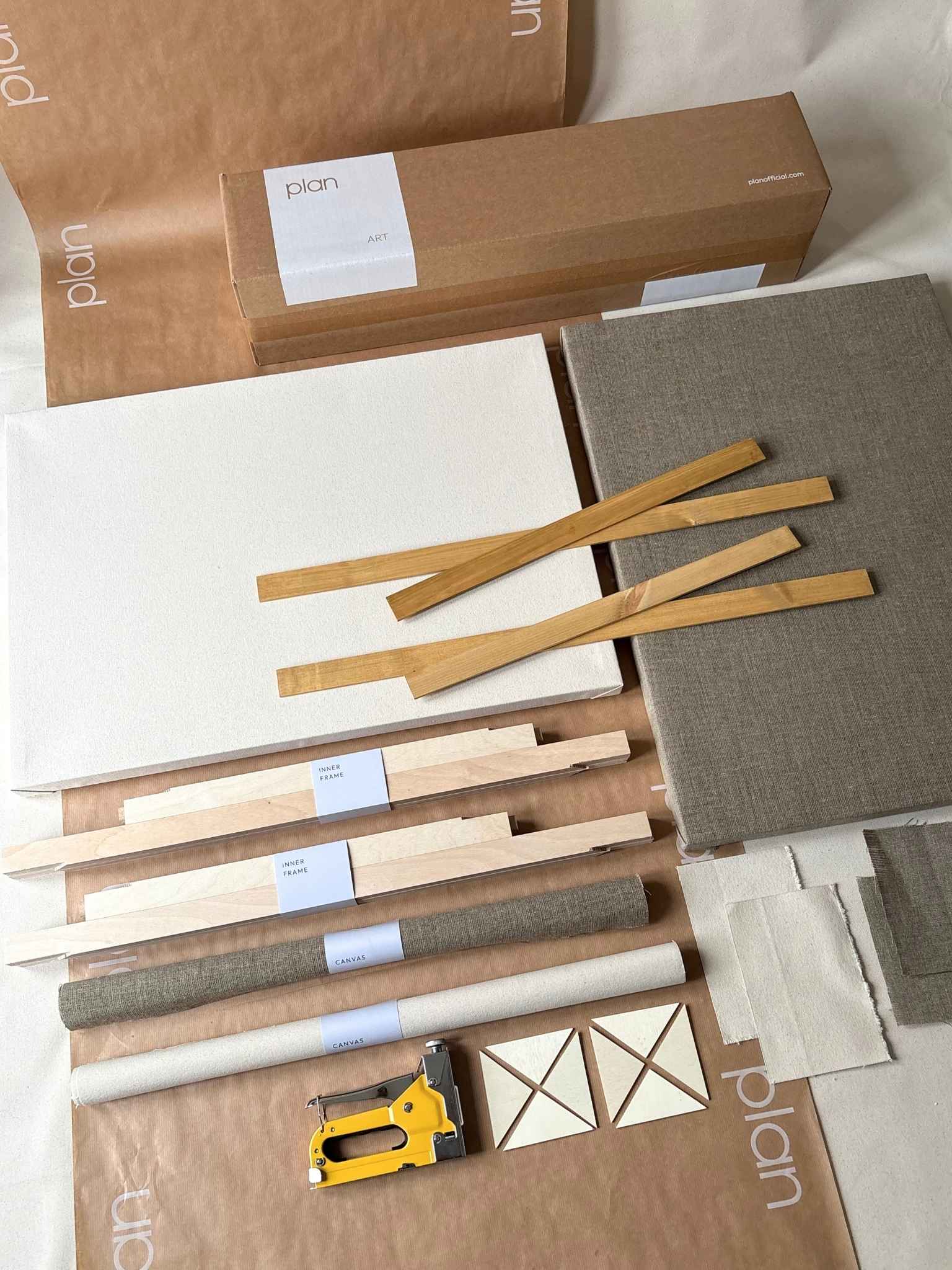 Build large framed canvases with double DIY framed canvas art kit by Plan with oak edge frame, featuring blank cotton and linen canvases, handcrafted inner frames, staple gun, canvas practice pieces and full kit contents arranged flat.