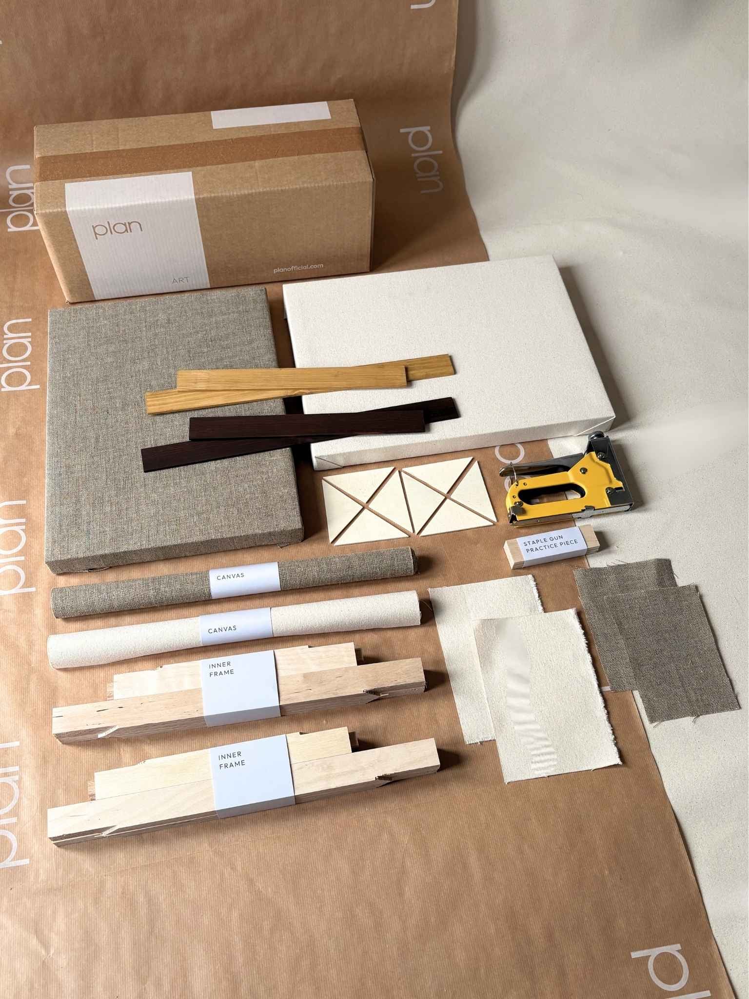 Styled framed blank canvas artworks leaning against a dark wooden sideboard, showing neutral cotton and linen canvases in oak and dark oak edge frames in a minimalist interior setting.