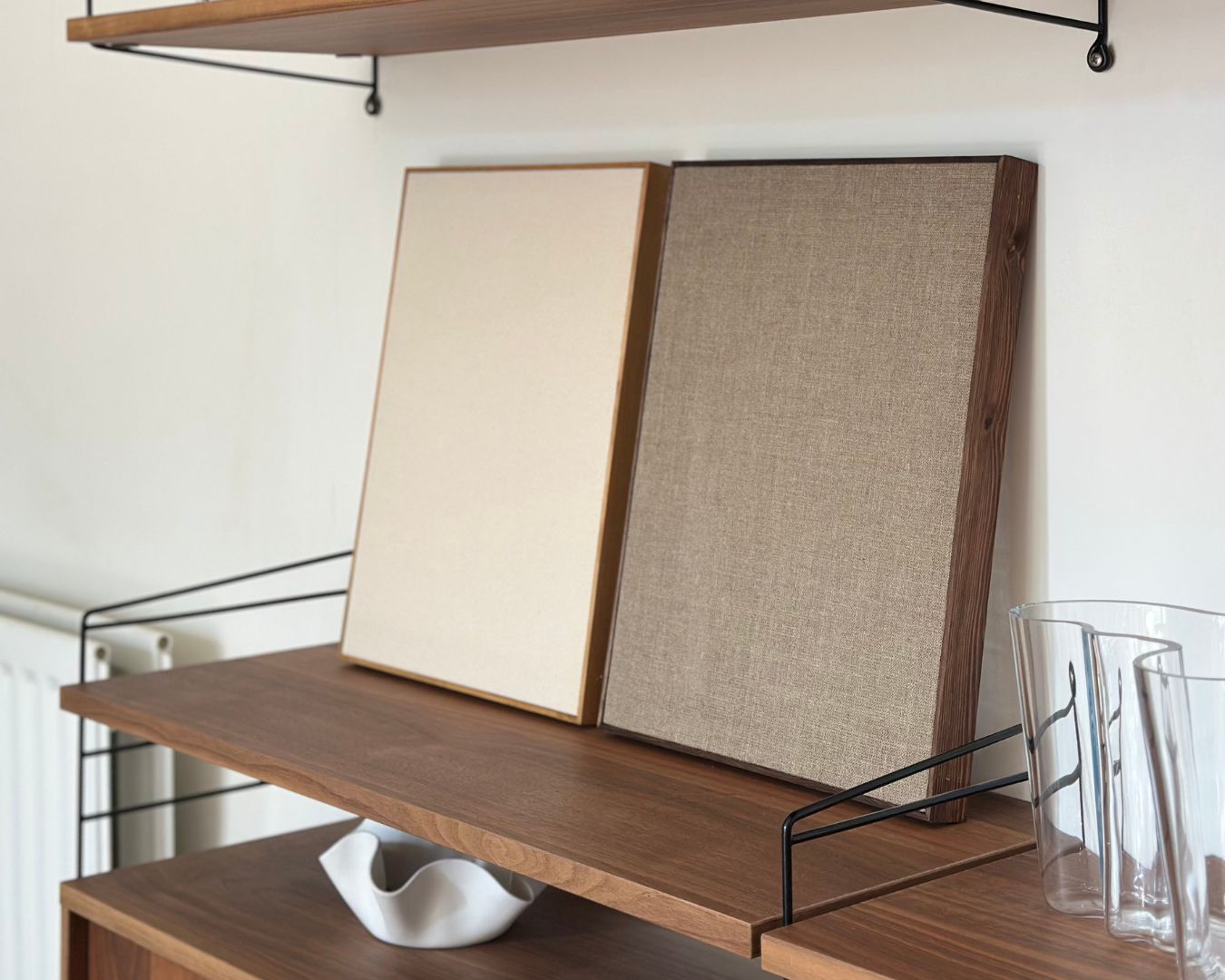 Two framed blank canvases in handcrafted wooden frames with natural cotton and linen, from Plan’s Blank Canvas Kits displayed on a wooden shelf. DIY art kits for adults offering a minimalist foundation for painting or creative projects.